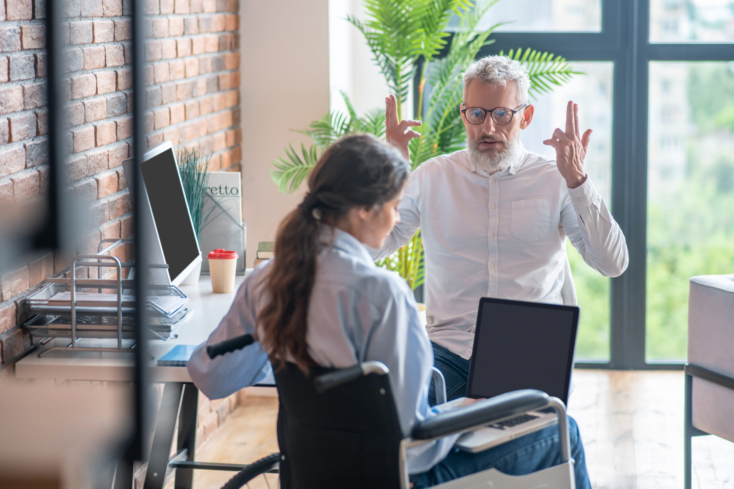 Handicapped young woman looking upset while her boss talking to her